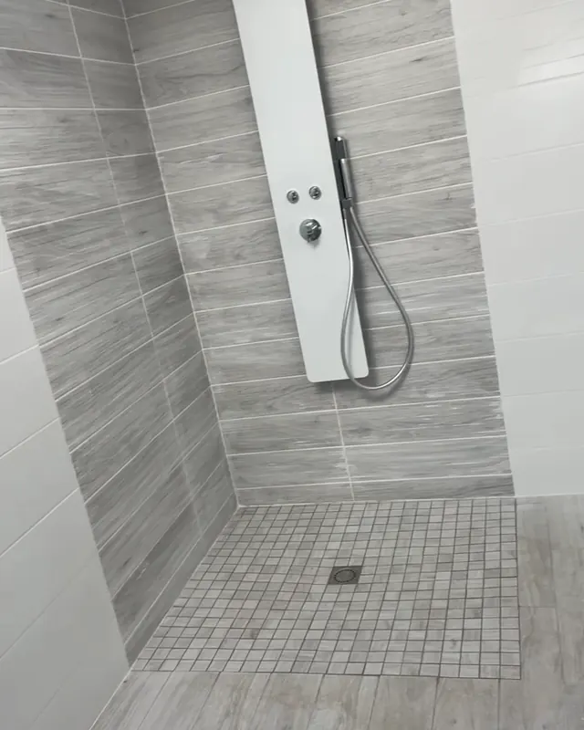 Douche carrelée avec colonne de douche blanche et receveur en mosaïque