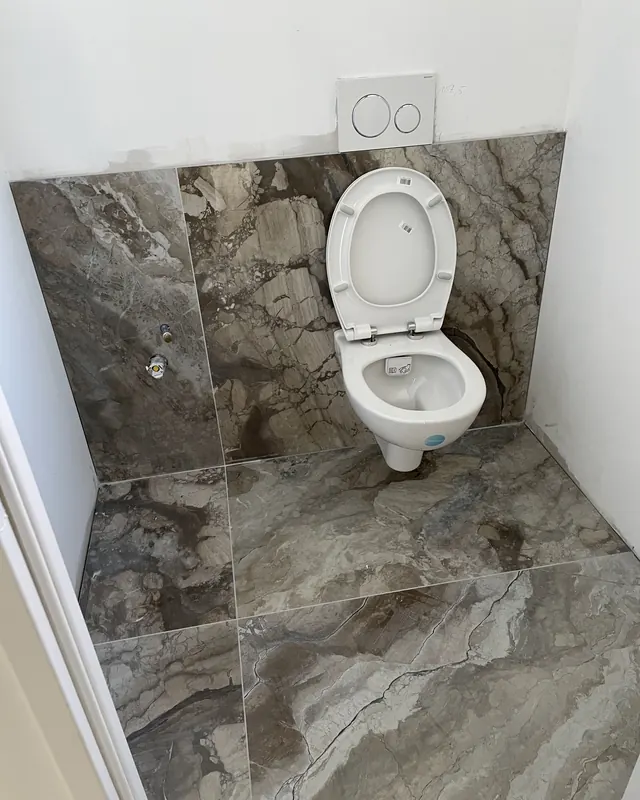 WC suspendu devant un mur en carrelage effet marbre