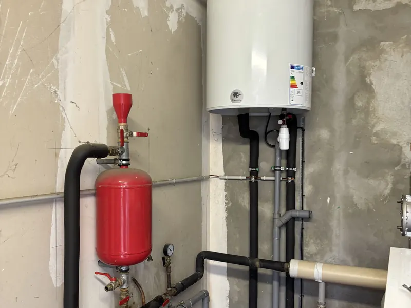 Chauffe-eau mural et deux vases d'expansion rouges raccordés en tuyauterie