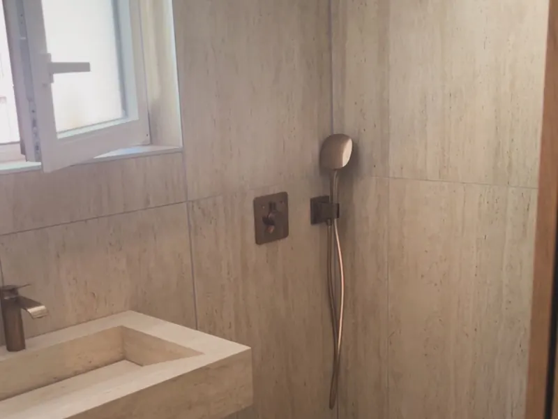 Douche carrelée avec pomme de pluie et vasque suspendue